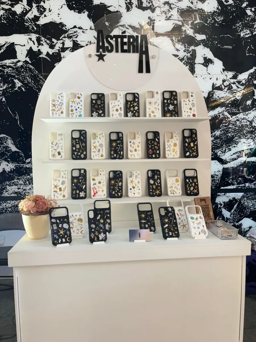 Stand de ASTÉRIA con fundas con charms blancas y negras en repisas